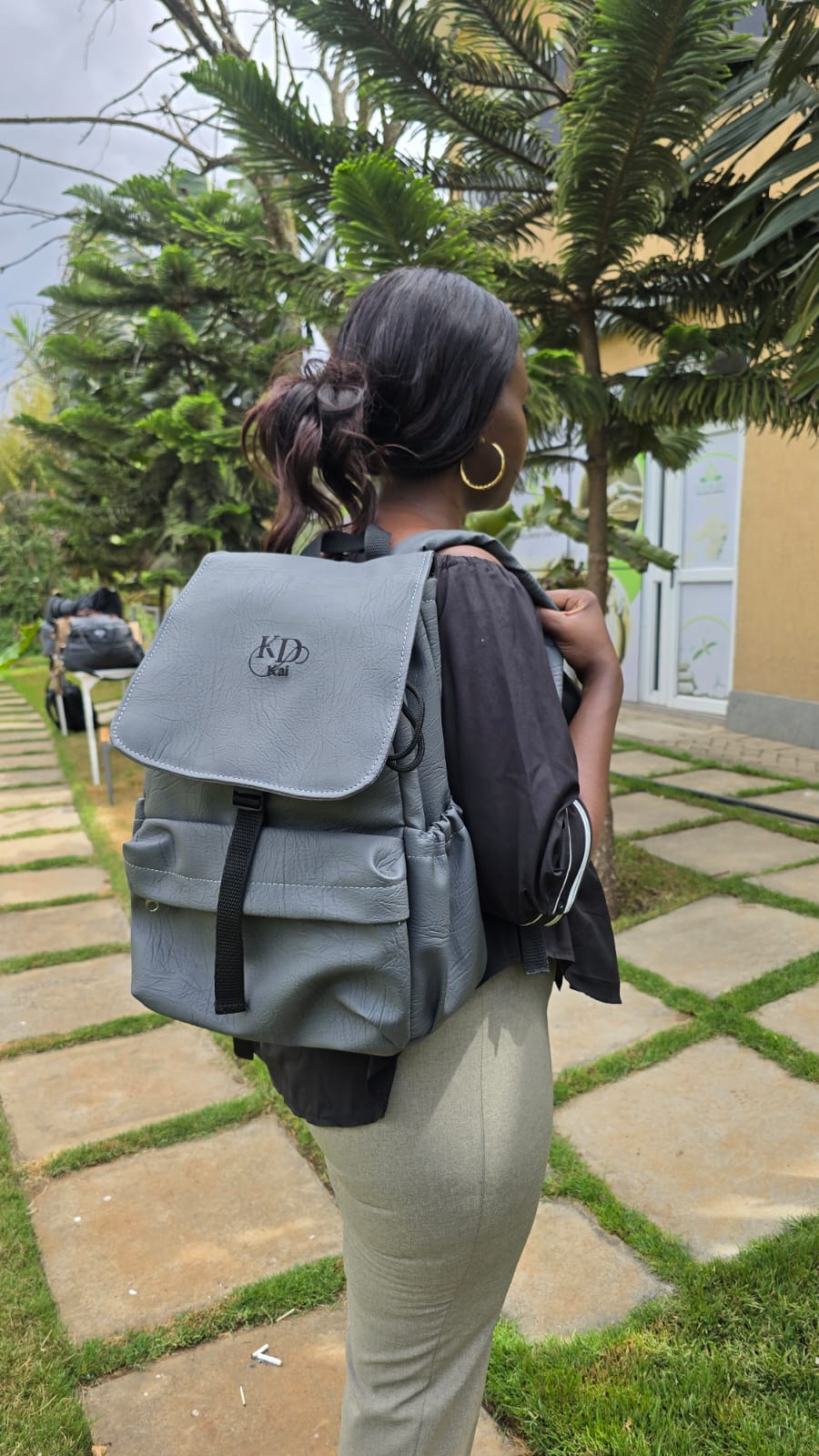 A woman carrying a grey Kai backpack in a garden